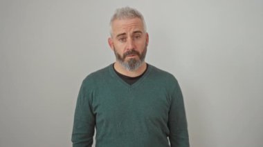 Süveter giymiş kafası karışmış genç bir adam, yüzünde şüpheci bir bakış, beyaz arka planda tek başına duruyor, ağzı açık iğneleyici bir şekilde şokta.