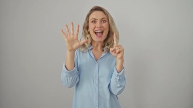 Tişört giyen neşeli genç bir kadın kendinden emin bir şekilde parmaklarıyla altı numarayı gösteriyor, güzel gülüşüyle ıssız beyaz bir arka planda parlıyor..