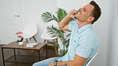 Dövmeleri olan gülen genç bir adam, rahat ve arkadaşça bir tavır sergiliyor..