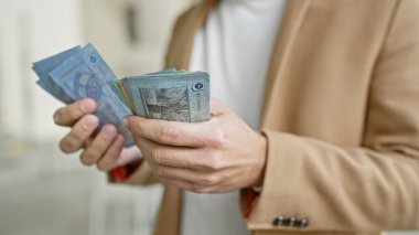 İspanyol adam şehir ortamında Malezya ringgit 'ini sayıyor, elindeki paraya odaklanıyor..