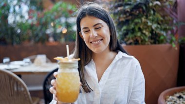 Genç ve güzel İspanyol kadın bar terasında tropikal kokteyl içiyor.