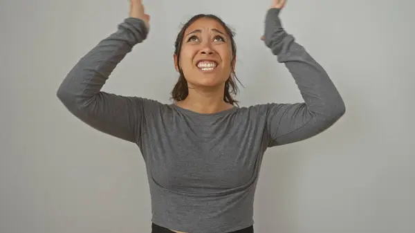 stock image An expressive hispanic woman stands against a white background, displaying a surprised reaction.