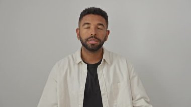 Beyaz arka planda tek başına duran genç Afrikalı Amerikalı adam, gömlek giyiyor, agresif bir şekilde çılgın bir ifadeyle bağırıyor, çılgın bir hayal kırıklığı, kollarını kaldırarak bağırıyor.