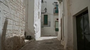 Ostuni, Puglia, İtalya 'da dar bir taş sokak. Beyaz duvarlar, yeşil kapılar, açık hava aydınlatması ve kırsal Avrupa cazibesi..