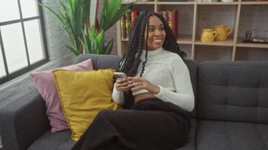 Genç bir kadın ve erkek, şık bir oturma odasında rahat bir kanepede kahve ve akıllı telefonlar eşliğinde rahat bir anın tadını çıkarırlar.