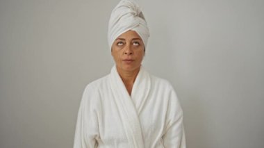 Bornoz ve havlu giymiş orta yaşlı bir kadın beyaz arka planda izole edilmiş intihar jestinde parmağını kafasına doğrultuyor.