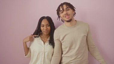 Mutlu, güzel bir çift pembe arka planda dikiliyor, kendini işaret ediyor, kendini sevdiriyor, mutlu ve gururlu bir gülümseme sergiliyor..