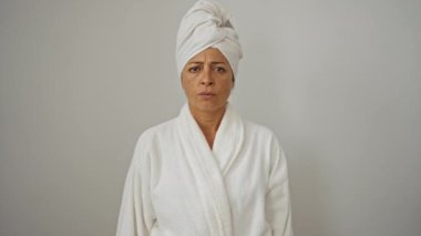Orta yaşlı kadın bornoz ve havlu giyiyor, somurtuyor ve üzgün, soyutlanmış beyaz arka plan, sorun yüzünden şüpheci ve gergin, yüzünde negatif ifade var.