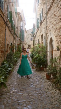 Genç İspanyol kadın Valldemossa, Mallorca, İspanya 'da büyüleyici bir kaldırım taşı caddesinde geziniyor. Etrafı yemyeşil saksı bitkiler ve geleneksel mimariyle çevrili..