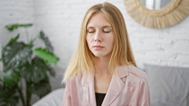 Huzurlu, genç bir kadın. Sarışın ve kapalı gözlü. Huzurlu bir ortamda, rahatlama ya da farkındalık tasvir eden..