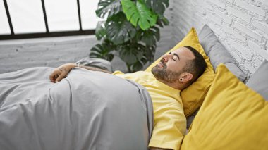 Yakışıklı İspanyol genç adam modern bir yatak odasında huzur içinde uyuyor.