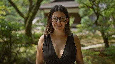 Neşeli ve kendinden emin, gözlüklü güzel bir İspanyol kadın dingin ginkaku-ji tapınağının yanında duruyor, neşeli gülüşü Kyoto 'nun zen bahçesinin güzelliğini kucaklıyor.