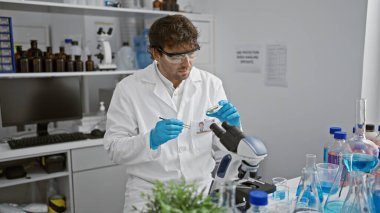 İyi donanımlı bir laboratuvarda numuneyi inceleyen yakışıklı bir bilim adamı.