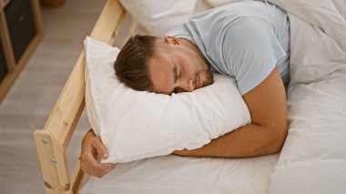 Sakallı genç İspanyol bir adam evdeki rahat yatak odasında uyuyor, dinleniyor ve dinleniyor.