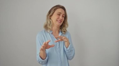 Tişört giyen, tiksindirici bir ifadeyle ayakta duran genç bir sarışın. İzole edilmiş beyaz arka plan üzerinde kaçınma reaksiyonu ile eller havaya.