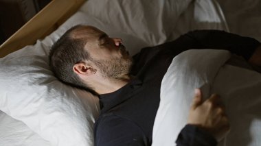 Kel sakallı, Latin bir adam geceleri karanlık bir yatak odasında huzur içinde uyuyor.
