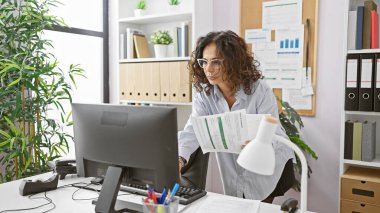 Modern ofis ortamında belgeleri inceleyen profesyonel bir İspanyol kadın..