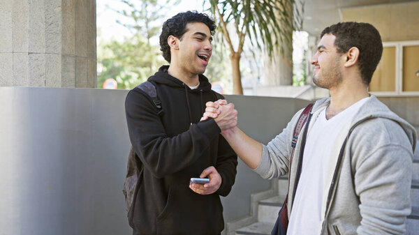 Двое мужчин счастливо здороваются друг с другом рукопожатием на городской улице.