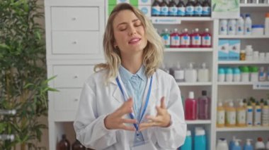 Tıbbi ürünlerle dolu bir eczanede duran beyaz önlüklü, kendinden emin genç bir kadın eczacı..