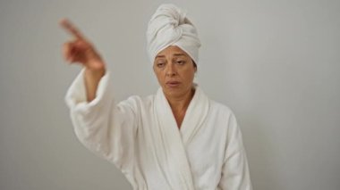 Orta yaşlı bir kadın havlu ve bornoz giyiyor. Alnında ezik jestleri olan insanlarla alay ediyor. Beyazlar üzerinde izole edilmiş.