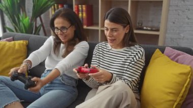 Bir anne ve kızı rahat bir oturma odasında birlikte gülüp oyun oynuyorlar..