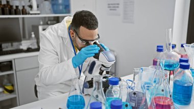 Laboratuardaki İspanyol bir adam mikroskopla örnekleri analiz ediyor, bilim, araştırma ve sağlık hizmetleri sunuyor..