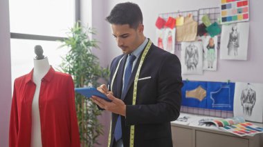 Sakallı profesyonel bir İspanyol terzi titizlikle bir tableti iyi organize edilmiş bir atölyede inceliyor..
