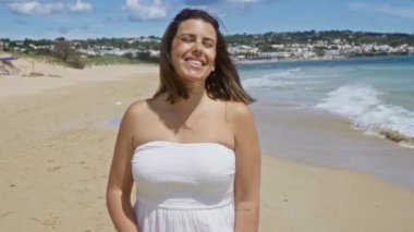 Beyaz elbiseli genç İspanyol kadın Salento, Puglia, İtalya 'da güneşli bir günde arka planda deniz ve köyle birlikte güneşli bir sahilde eğleniyor..