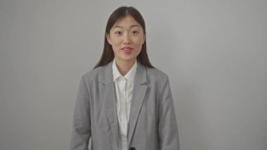 Muzaffer genç Çinli kadın beyaz ceketle kutlama yapıyor ve sevinçlerini ifade ediyor. İzole edilmiş beyaz arka planda mutlu bir şekilde duruyor.