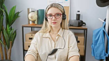 Ofis ortamında kulaklık takan sarışın bir kadın, müşteri hizmetlerini canlandıran ya da telefonla satış yapan profesyonel bir kadın..