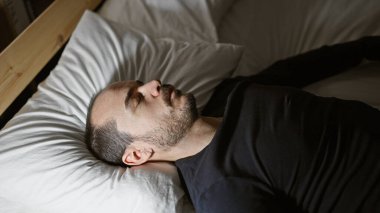 Sakallı, orta yaşlı kel bir adam gecenin geç saatlerinde karanlık bir yatak odasında huzur içinde uyuyor..