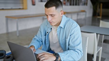 Üniversite kütüphanesinde laptopta çalışan yakışıklı bir İspanyol.