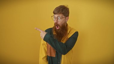 Kızıl saçlı ve sakallı, sarı arka planda dikilen şaşırmış genç bir adam..