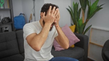 Sakallı adam, oturma odasındaki kazada kan kaybediyor.