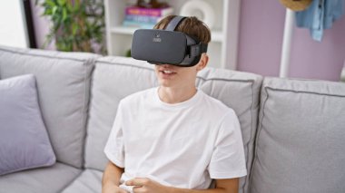 Sanal gerçeklik kulaklığı takan sarışın çocuk kapalı bir koltukta oturuyor.