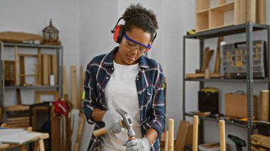 Odaklanmış kadın marangoz atölyede çekle çalışıyor.