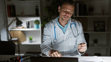 Yakışıklı İspanyol erkek doktor geç saatlere kadar klinikte çalışıyor, kendini adamış sağlık uzmanlarını gösteriyor..