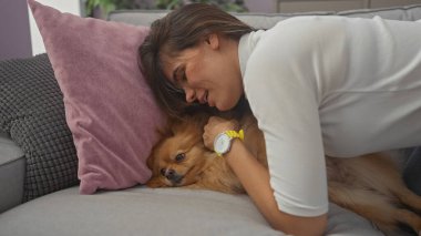 Genç bir İspanyol kadın, Pomeranian köpeğini sevgiyle kucaklar rahat bir oturma odasında, şefkat ve arkadaşlık gösterir..