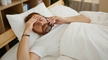 Sakallı, olgun bir adam yatak odasında telefonla konuşurken kendini iyi hissetmiyor..