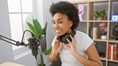 Radyo stüdyosunda kulaklık takan gülümseyen Afrikalı Amerikalı kadın.