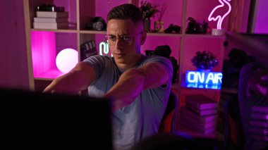 Genç İspanyol bir adam geceleri modern, neon ışıklı, kapalı bir oyun odasında kollarını açıyor..