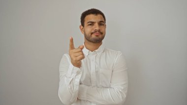 Beyaz tişörtlü genç İspanyol bir adam izole edilmiş beyaz bir arka plana karşı duruyor ve kendine güvenen bir ifade öne bakıyor.