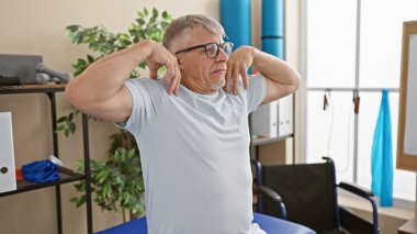 Olgun bir adam, boyun kaslarını iyi donanımlı bir rehabilitasyon kliniğinde çalıştırır.