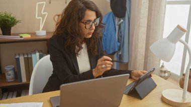 Ev bilgisayarında çalışan orta yaşlı bir kadın modern bir dairede dijital tableti inceliyor..