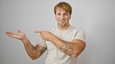 Dövmeleri olan gülümseyen genç bir adam izole edilmiş beyaz bir arka plana güvenerek, sıradan bir cazibe yayıyor..