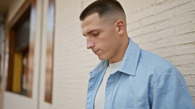 Şehir arka planında bulanık bir şehir sokağının yanında günlük mavi ceketli, düşünceli bir genç adam poz veriyor..