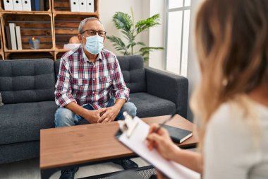 Kendine güveni tam, beyaz saçlı, ayık bir ifade ve kararlı bir tavırla bir psikoloji kliniğinde maske takmış kendini beğenmiş bir son sınıf öğrencisi.