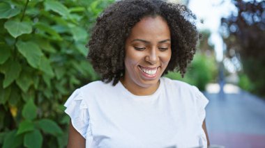 Doğal saç stili olan gülümseyen Afro-Amerikan kadın.