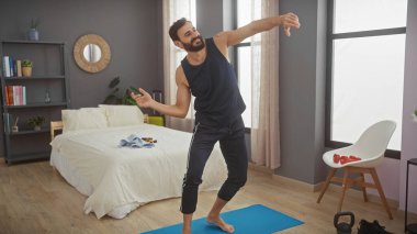 Çekici, orta yaşlı bir adam modern odasında keyfi bir şekilde dans ediyor ve rahat bir ortam yaratıyor..