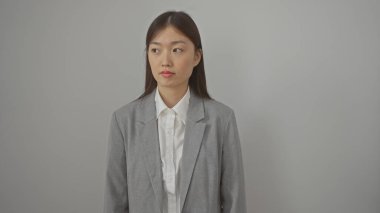 Tarafsız bir ifade ve modern moda tasvir eden beyaz bir arkaplan karşısında profesyonel Asyalı genç bir kadının portresi.